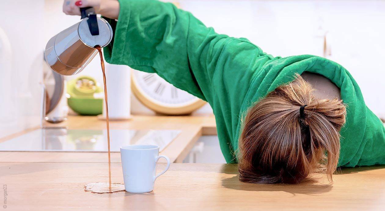 Zmęczona kobieta próbuje nalać kawy do kubka i ją rozlewa