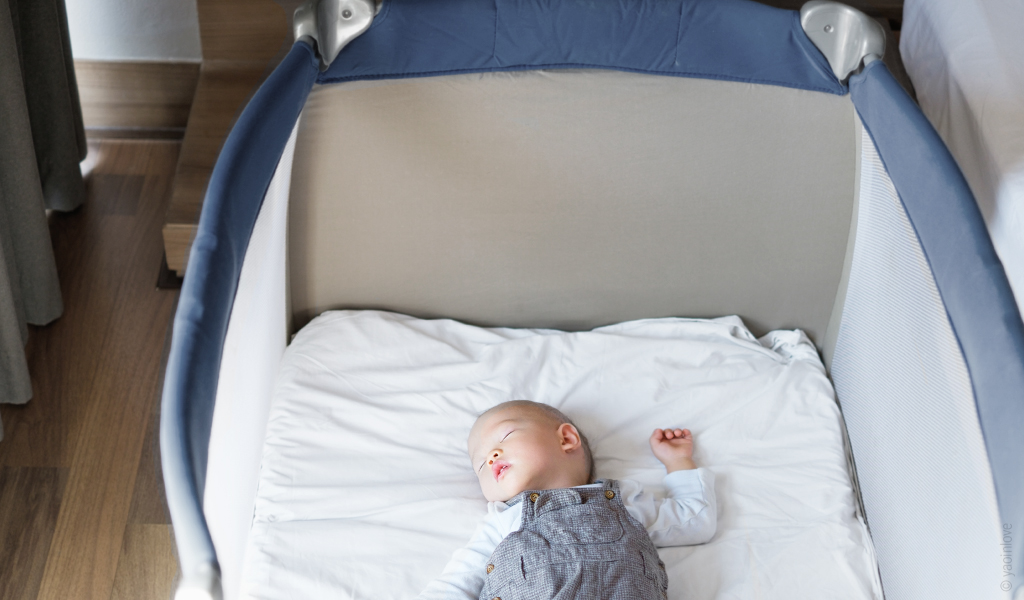 Materac dziecięcy 60x120 cm w łóżeczku podróżnym, w którym leży niemowlę.